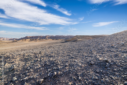 Wide-angle view of yardang landforms under dramatic white clouds and blue sky in Dahaidao, Gobi Desert, Xinjiang, China
