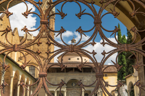 a rusty and weathered wrought iron fence and blurred image of the basilica of santa croce