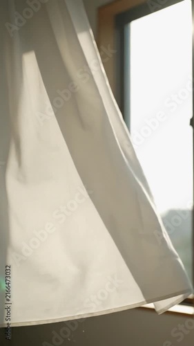 White curtain blowing gently in the breeze with soft window light in a modern home interior