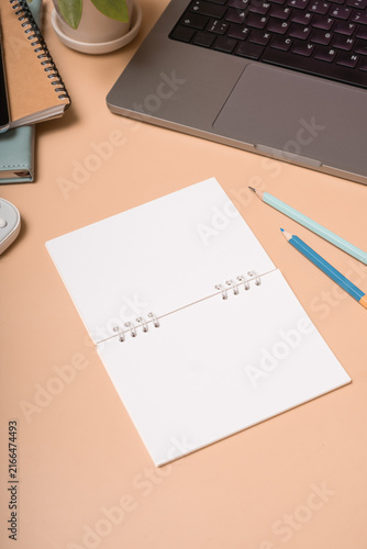 Workspace with blank notebook, tools, and laptop on a desk