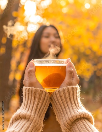 Woman Holding Warm Drink in Autumn Forest