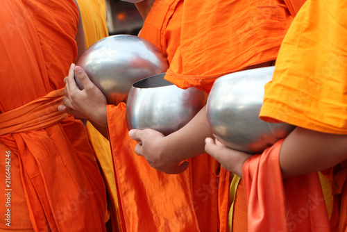 Fotografie Buddhist monks holding alms bowls during morning alms giving in Thailand