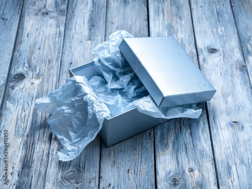 Open Gift Box With Tissue Paper Spilling Out On Rustic Wooden Boards