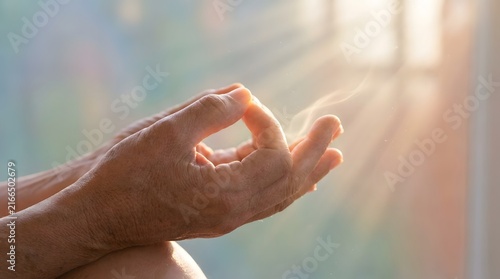 Close-up of a hand gently resting near a bright sunlit window with soft natural light