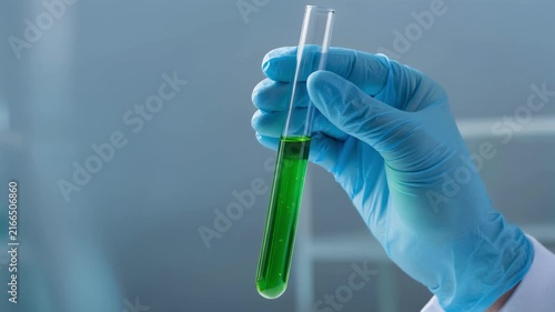 Scientist holding test tube with green liquid in laboratory research experiment