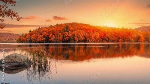 Beautiful autumn forest landscape with colorful fall foliage reflected on calm lake at sunset