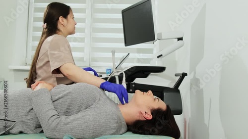 Doctor moves probe along patient neck conducting ultrasound scanning in clinic. Woman lies still trusting expert at procedure in hospital
