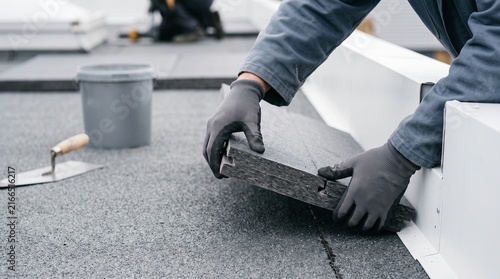 Hands seal a thermal joint in roof insulation boards