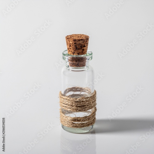 A small empty glass bottle decorated with twine and cork