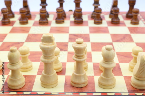Wooden chess board. White and black pieces. Start or early beginning concept.