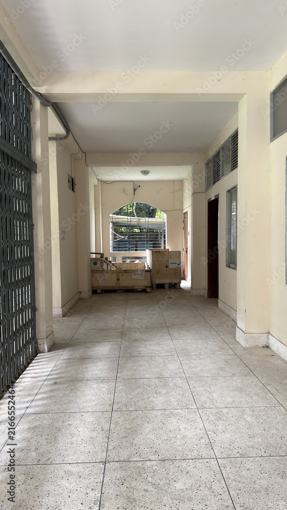Fototapeta premium A long empty corridor with a gate and stacked wooden boxes