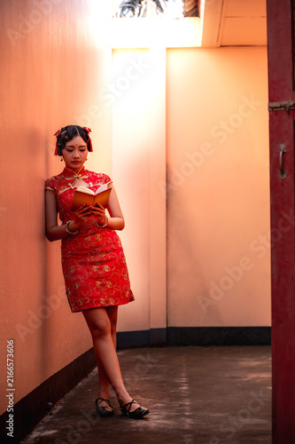 Fotografía Young Chinese woman wearing a stylish traditional red Qipao dress reading book a
