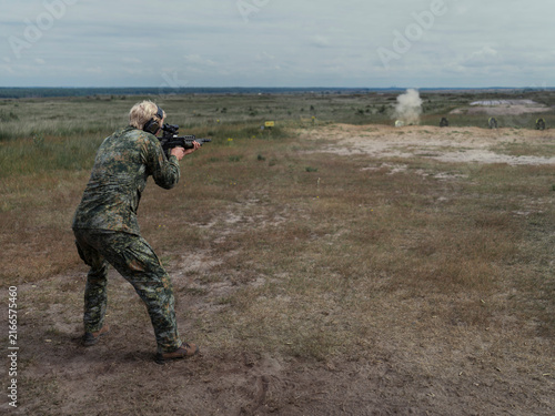 Obraz na plátně A Dutch soldier in NFP fractal camouflage fires a British bullpup assault rifle from the standing position during allied live fire training
