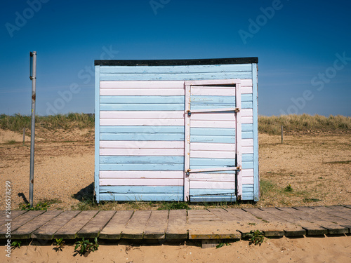 Obraz na plátne Pale blue and pink beach hut by the boardwalk at Great Yarmouth beach on a sunny