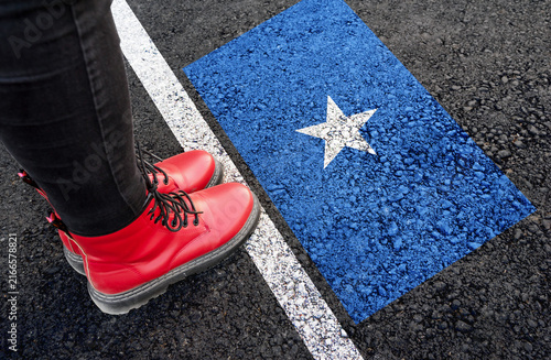 Bild auf Leinwand a woman with a boots standing on asphalt next to flag of Somalia and border