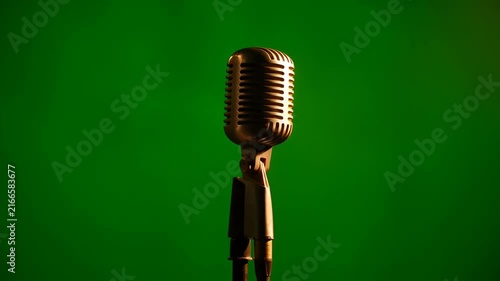 Vintage microphone on green screen with dramatic spotlight for performance or recording
