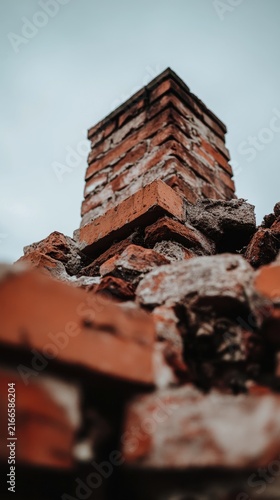 Crumbling old brick chimney closeup with damaged masonry against gray sky