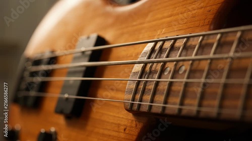 Close-up shot of a wooden electric bass guitar fretboard and strings, music performance, studio, concert, blues, rock, jazz, professional audio equipment