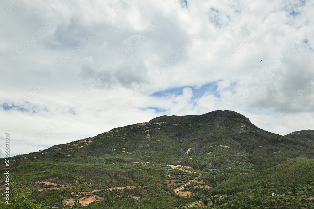 Fototapeta premium Green Mountain Slopes Under Clouds and Blue Sky