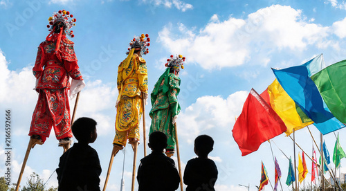Traditional Chinese stilt walkers in colorful costumes at outdoor festival parade