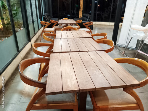 Empty wooden dining tables and chairs arranged in a cafe interior, ready for guests in a hospitality setting