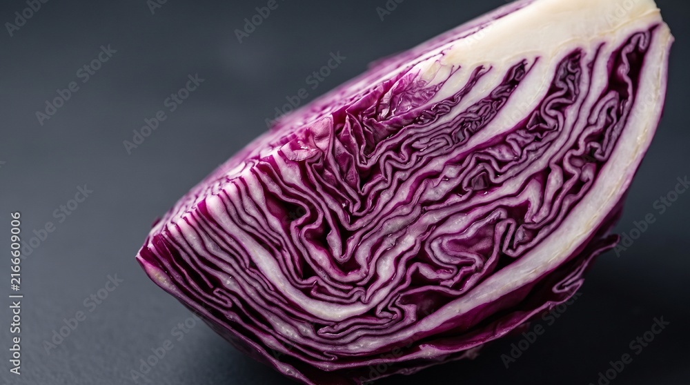 Obraz premium Fresh red cabbage wedge on dark background, sliced purple cabbage cross section, organic vegetable for healthy cooking and salad preparation