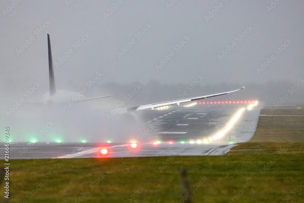 Naklejka premium Airplane taking off in heavy rain on wet runway