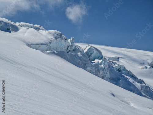 Snow-covered glacier crevasse beneath a clear blue sky