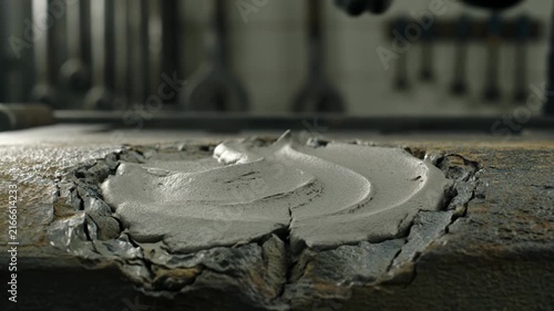 Close-up of gloved hand smoothing concrete filler into a damaged rusty metal surface, industrial repair and restoration concept