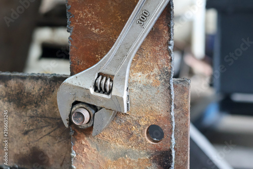 Photography Adjustable wrench tightening a metal nut on a rusty plate.