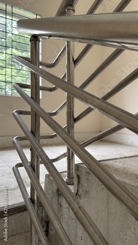 Shiny metal railing alongside concrete stairs inside a building interior