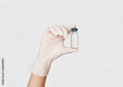 Hand in Medical Glove Holding Glass Vial in Laboratory
