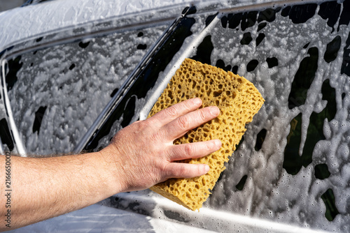 Hand wash car window with sponge and soap foam