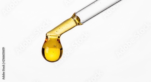 Macro shot of a thick golden cannabis distillate droplet falling from a glass applicator against a clean white professional background, medical, distillate, dabbing