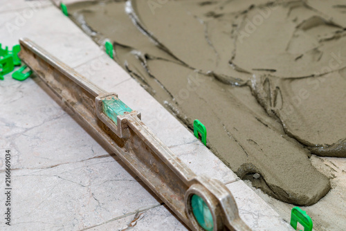 Photography A construction level and plastic tile leveling systems lie next to freshly applied adhesive mortar