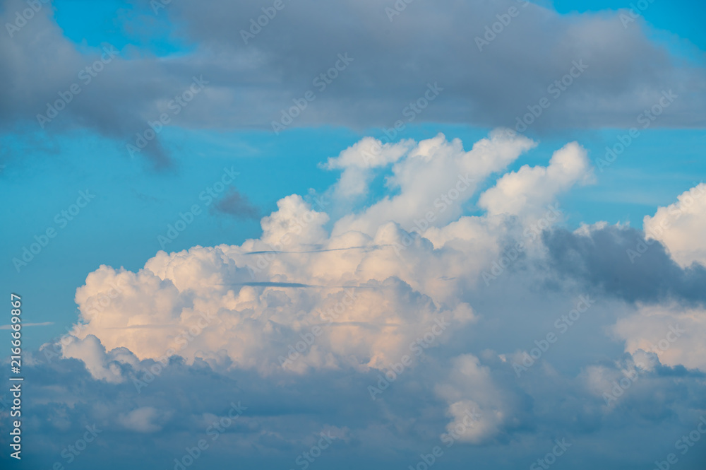 Fototapeta premium Fluffy white clouds and dark storm clouds floating across a vibrant blue sky, captured from Mount Shizitou in New Taipei City, Taiwan.