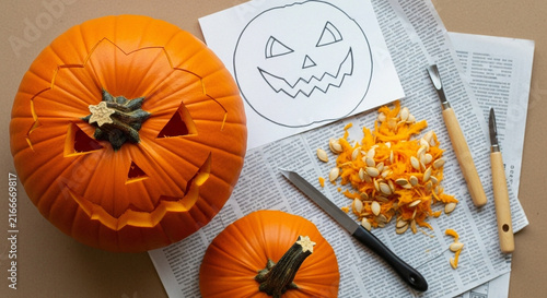 Top-down pumpkin carving in progress with tools and seeds