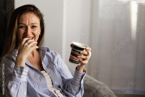 Canvastavla Woman enjoys hot drink while sitting at home and smiling during morning hours on