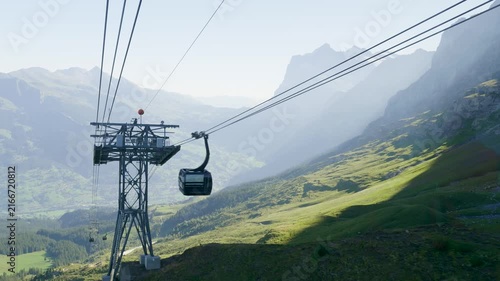 Gondola descending along a cable past a pylon with a breathtaking mountain landscape in the background. Switzerland