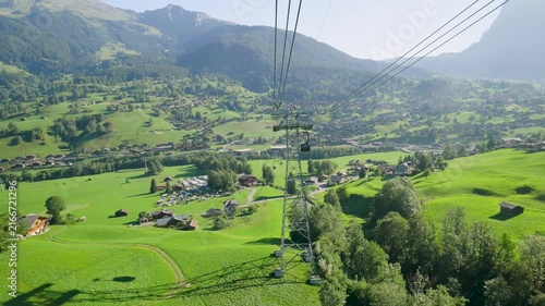 Gondola ascending over the green swiss alpine valley of grindelwald on a sunny summer day. Switzerland