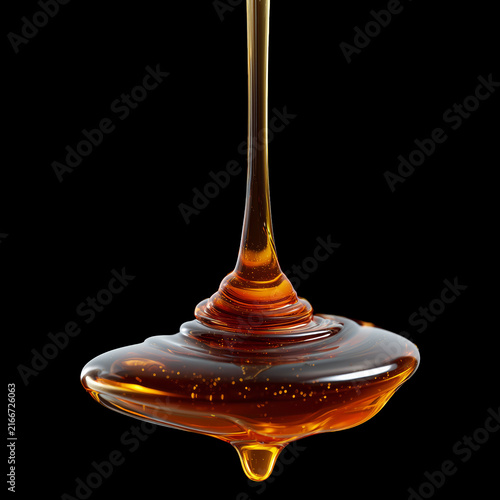 Maple syrup amber liquid dripping isolated on black background, concept of condiments and sweets
