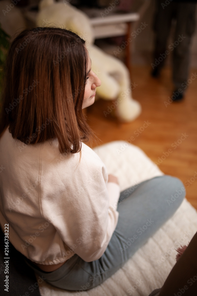 Fototapeta premium Woman Sitting in a Cozy Living Room Setting With a Warm Atmosphere