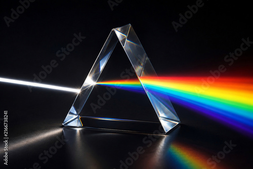 Light Refracting Through Glass Triangular Prism Creating Rainbow Spectrum on Dark Background