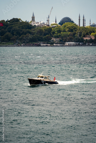 Photography Side view of a fast motorboat sailing on sea water with Istanbul city skyline in the background