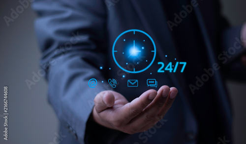 24/7 customer support service, non-stop business operation, and call center concept with businessman holding glowing clock icon and contact symbols.