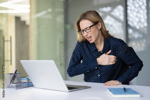 Foto Businesswoman experiencing sudden chest pain or heart attack symptoms while work