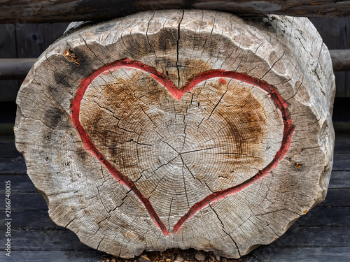 Red heart painted on weathered tree trunk slice