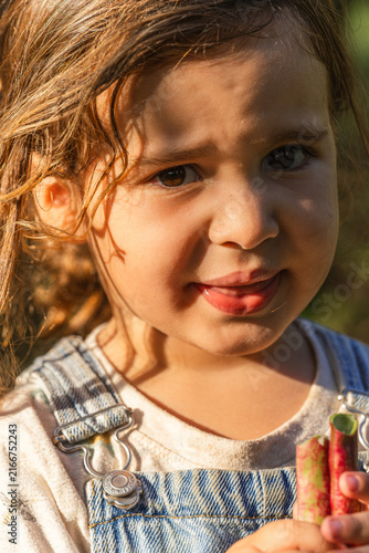 Sunlit girl smiles softly, holding colorful crayons