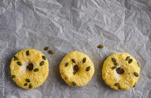 Top view of homemade cottage cheese bagels topped with pumpkin and sesame seeds on baking paper, healthy low carb keto diet breakfast concept