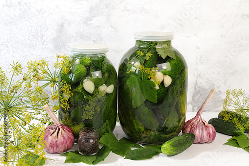 Cuadro en lienzo Jarred cucumbers with dill, garlic, and pickling leaves on the kitchen counter